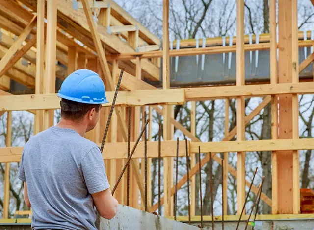 Smiths Falls Building Bylaw - tweaks Stock image of a contractor looking at plans for a house that studs are being set up.