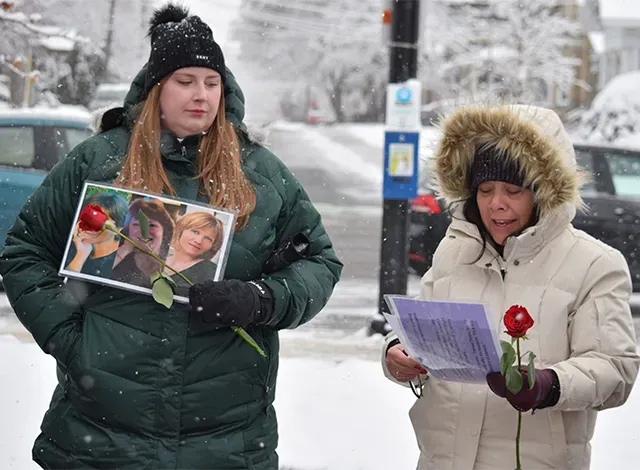 Emma Kinsmen holding a picture of 3 women and Erin Lee reading for a piece of paper while holding a single rose.