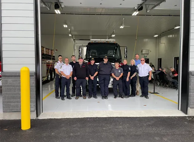 Rideau Lakes fire fighters posing in the truck bay in front of a fire engine.