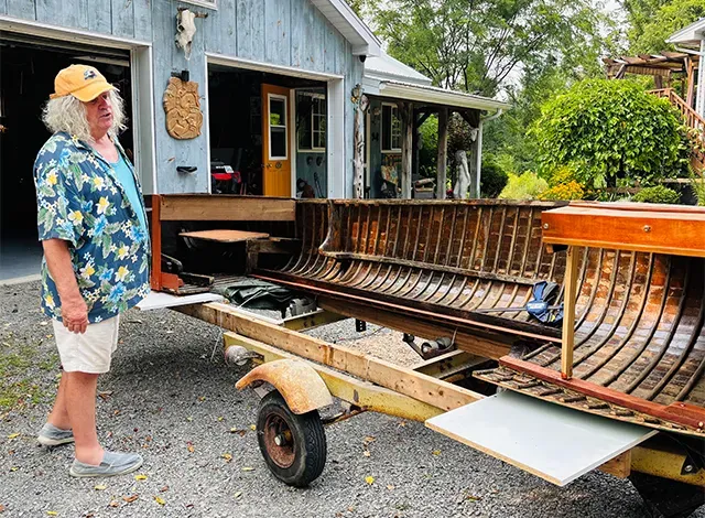 James Graham standing in front of an old boat being turning into a bar.
