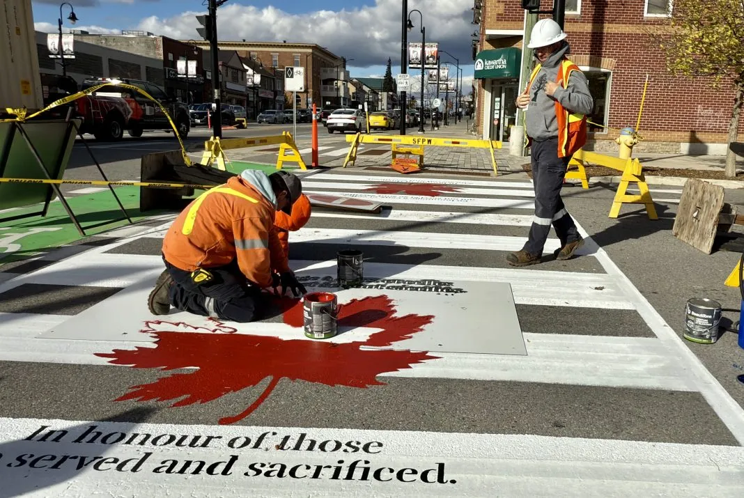Public Works employees painting the Smiths Falls veterans' crosswalk